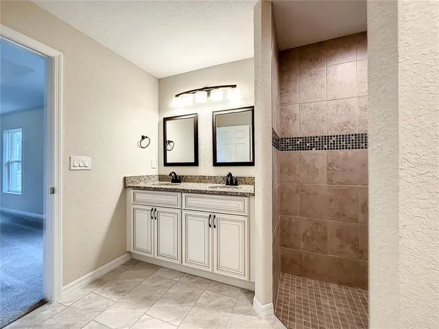 a bathroom with a granite countertop sink a mirror and shower