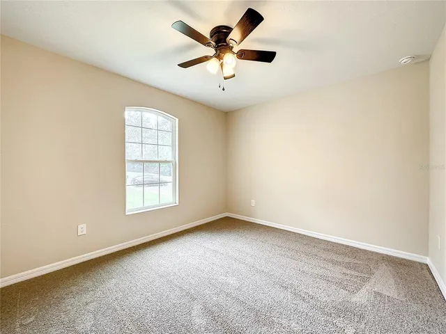 an empty room with windows and ceiling fan