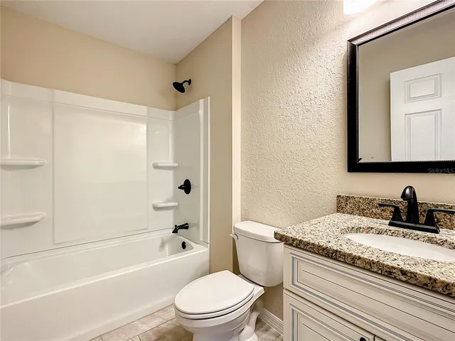 a bathroom with a granite countertop toilet a sink and a bathtub