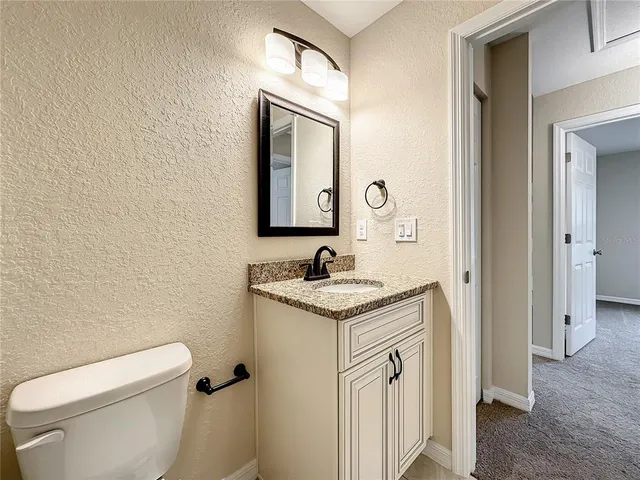 a bathroom with a granite countertop toilet sink and mirror
