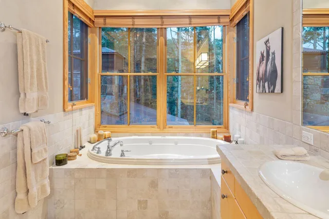 a bathroom with a granite countertop sink and a bathtub next to a window