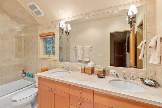 a bathroom with a double vanity sink toilet and a mirror