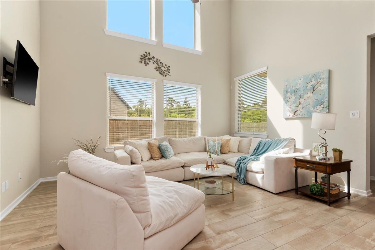 17814 Tree Of Heaven Conroe, TX 77385 - Photo 2 of 48 Light-filled living room with soaring two-story ceilings, expansive windows, and an open layout. Features tile flooring and a spacious seating area—perfect for relaxing or entertaining.