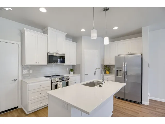a kitchen with kitchen island a white counter top space stainless steel appliances and cabinets