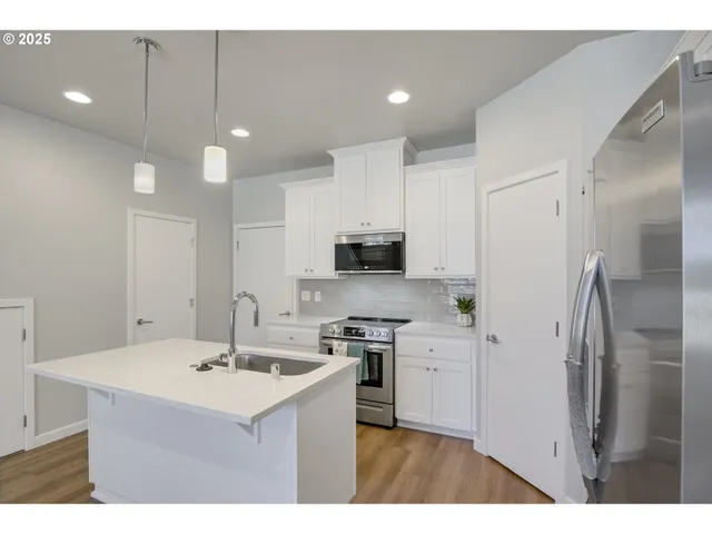 a kitchen with stainless steel appliances a sink a stove a refrigerator and cabinets