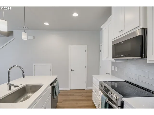 a kitchen with a sink and a stove top oven with wooden floor