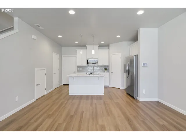 a view of kitchen with granite countertop refrigerator oven sink and white cabinets with wooden floor
