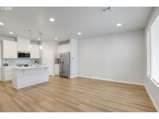a view of kitchen with kitchen island granite countertop a stove top oven a sink and a refrigerator with wooden floor