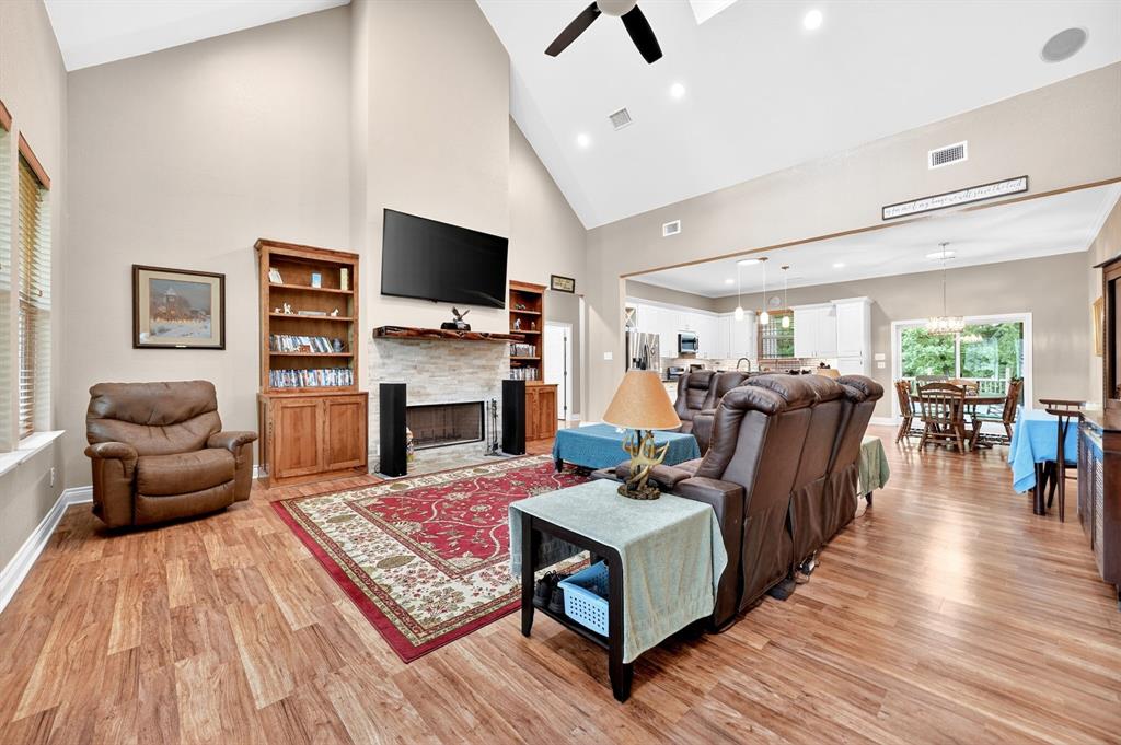 5230 Esquire Estates Road Mabank, TX 75156 - Photo 7 of 39 Spacious living area featuring vaulted ceilings, wood-finish flooring, and a stone-faced fireplace with a natural wood mantle