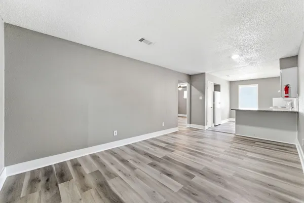 a view of an empty room with window and wooden floor