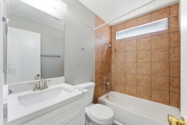 a bathroom with a bathtub shower sink vanity mirror and toilet