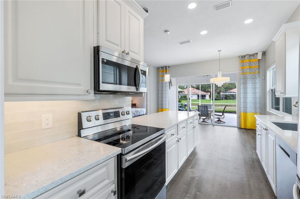 4648 Rio Poco Court Naples, FL 34109 - Photo 15 of 27 Kitchen with appliances with stainless steel, white cabinets, decorative backsplash, and recessed lighting