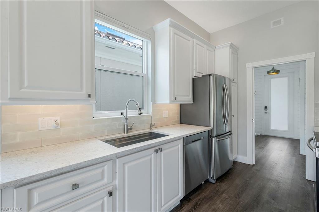 4648 Rio Poco Court Naples, FL 34109 - Photo 16 of 27 Kitchen with stainless steel appliances, a sink, white cabinetry, and tasteful backsplash