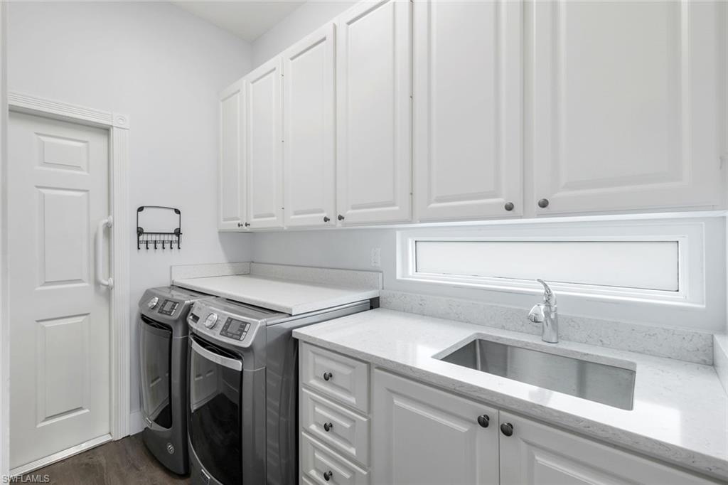 4648 Rio Poco Court Naples, FL 34109 - Photo 18 of 27 Washroom featuring independent washer and dryer, cabinet space, and wood-style floors. Note: Dated glass bricks replaced with beautiful Impact Glass.
