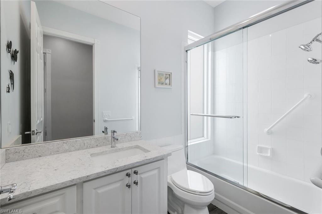 4648 Rio Poco Court Naples, FL 34109 - Photo 22 of 27 Guest Bathroom with vanity, toilet, and enclosed tub / shower combo. Note: Dated standard glass bricks were replaced with beautiful Impact Glass.