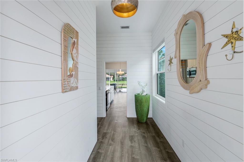 4648 Rio Poco Court Naples, FL 34109 - Photo 4 of 27 Corridor with Shiplap paneling walls and dark luxury vinyl finished floors