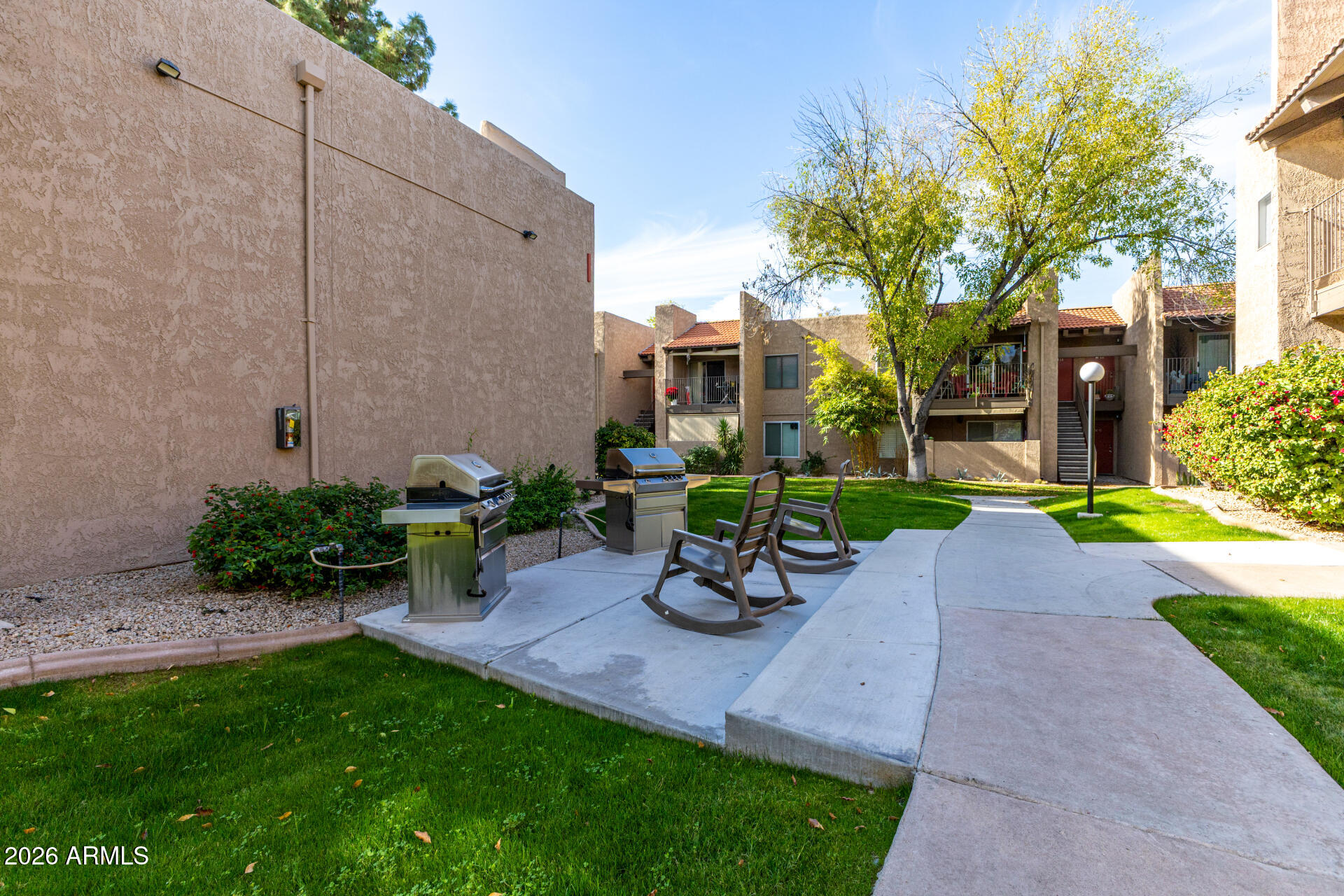 5525 East Thomas Road, Unit H7 Phoenix, AZ 85018 - Photo 23 of 27 a view of a backyard with a table and chairs under an umbrella