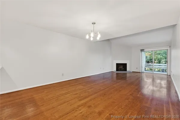 an empty room with wooden floor chandelier and windows