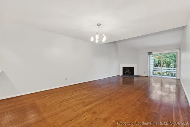 an empty room with wooden floor chandelier and windows