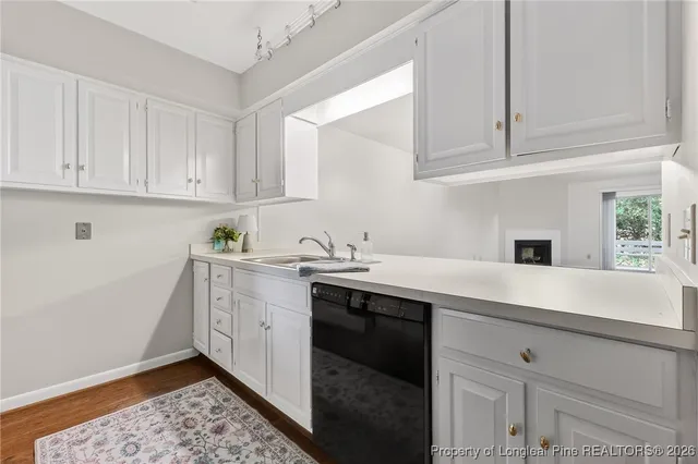 a kitchen with stainless steel appliances granite countertop a sink and dishwasher with white cabinets