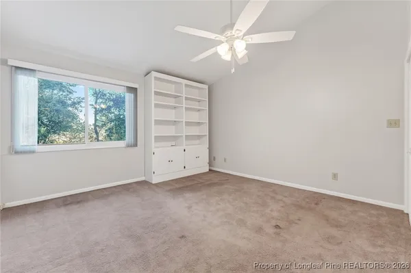 an empty room with windows and chandelier fan