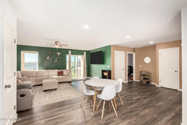 a living room with furniture a large window and wooden floor