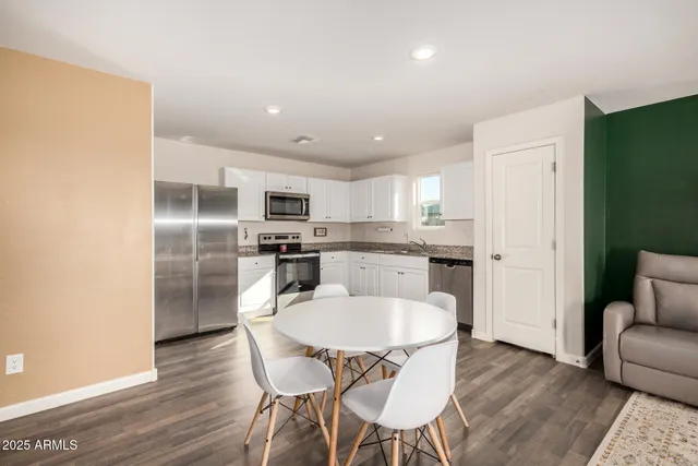 a kitchen with stainless steel appliances granite countertop a dining table chairs refrigerator microwave and cabinets