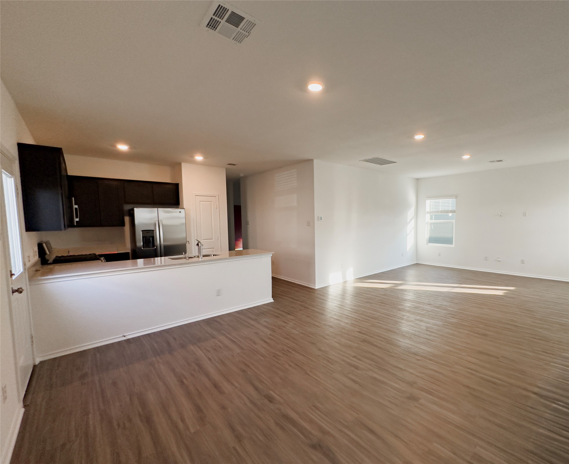 312 Soapstone Pass Maxwell, TX 78656 - Photo 5 of 21 Open-concept layout featuring wood-finish flooring, recessed lighting, and a kitchen with dark cabinetry and stainless steel appliances