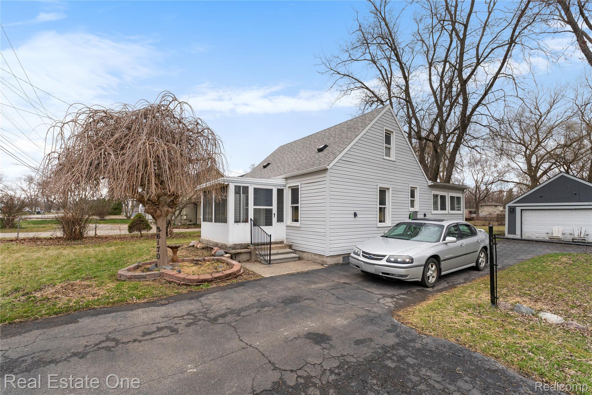 26170 Wick Road Taylor, MI 48180 - Photo 2 of 16 View of side of home with a yard, a sunroom, an outdoor structure, roof with shingles, and a garage