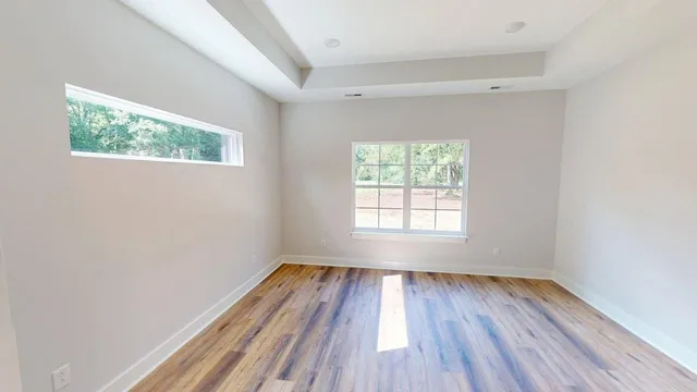 an empty room with wooden floor and windows