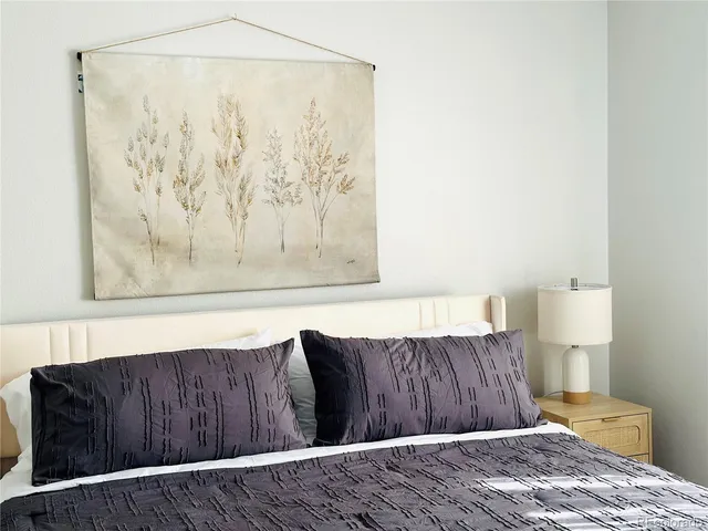 a bedroom with a bed and a lamp on the dresser