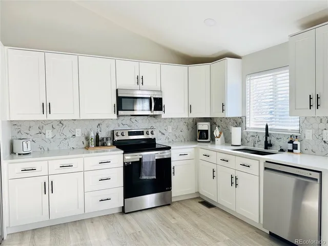 a white kitchen with granite countertop white cabinets a sink and dishwasher