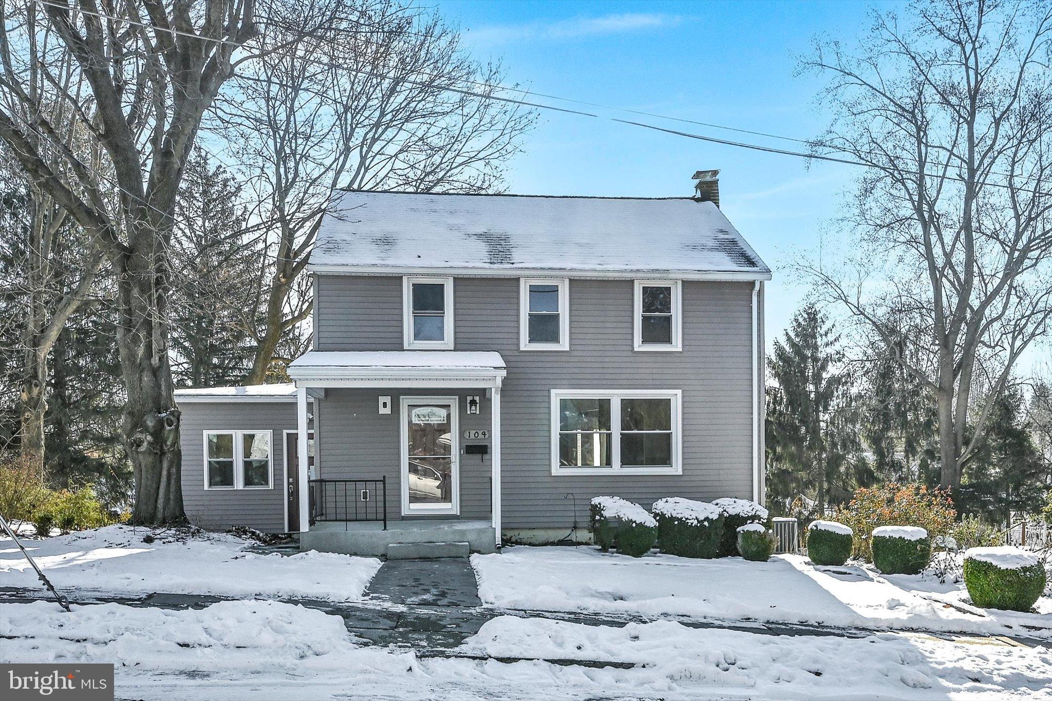 a front view of a house with a yard and large tree