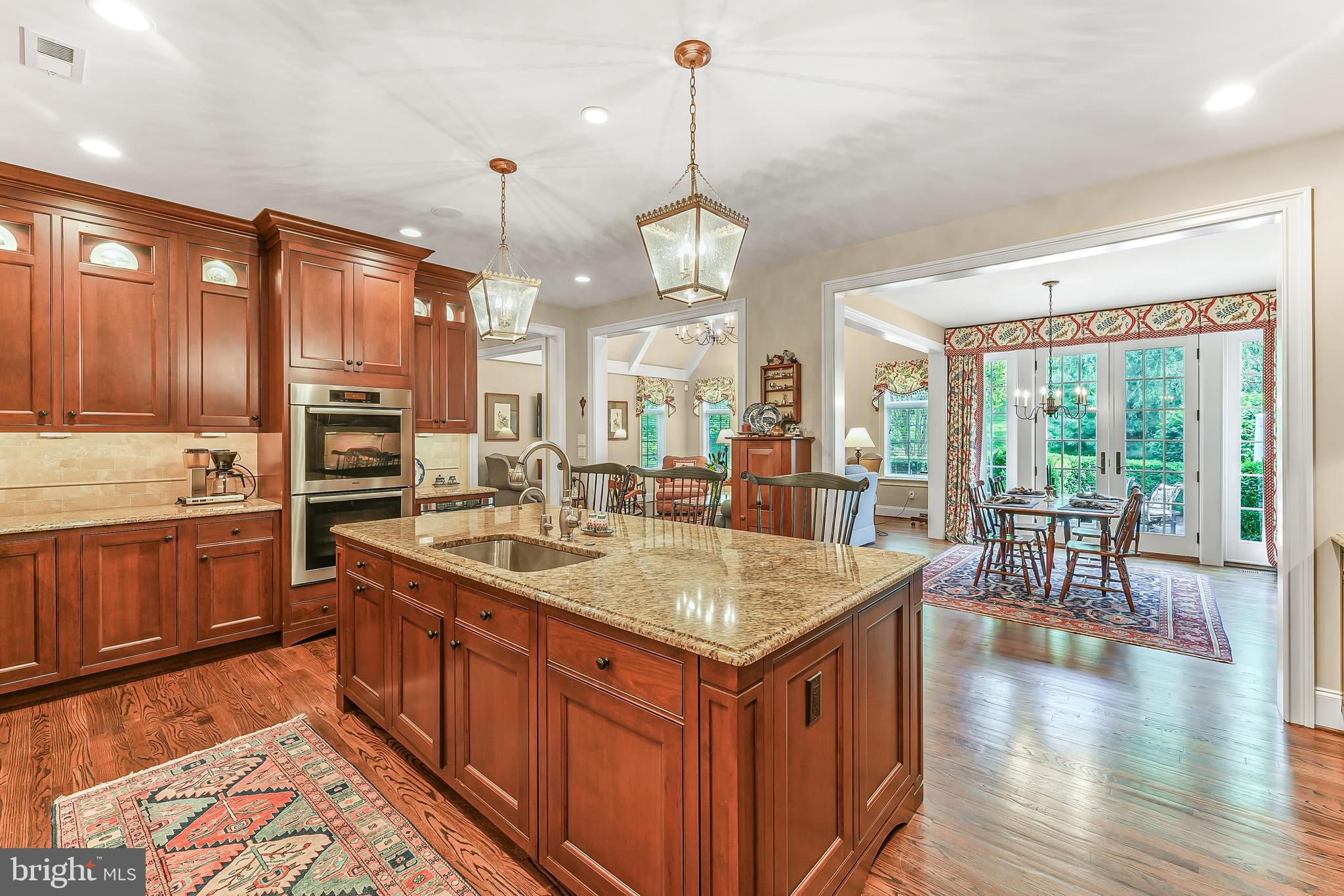 217 Valley Ridge Road Haverford, PA 19041 - Photo 9 of 49 a kitchen with stainless steel appliances granite countertop a kitchen island a stove a sink a dining table and chairs with wooden floor