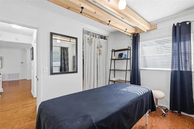 a bedroom with a bed and a chair with the wooden floor