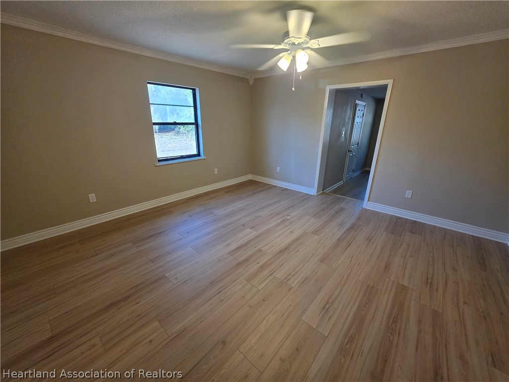 2858 North Lancaster Road Avon Park, FL 33825 - Photo 9 of 13 an empty room with wooden floor chandelier fan and windows