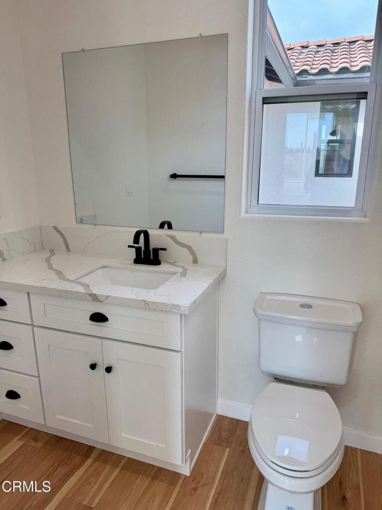 1170 West 1st Street Oxnard, CA 93030 - Photo 14 of 27 a bathroom with a toilet a sink and mirror