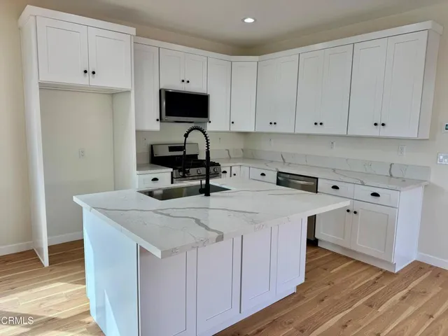 a kitchen with white cabinets sink and stove