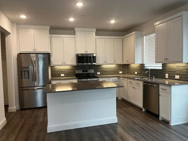a kitchen with kitchen island granite countertop appliances cabinets and a sink
