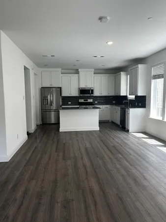 a kitchen with stainless steel appliances wooden floors and view living room