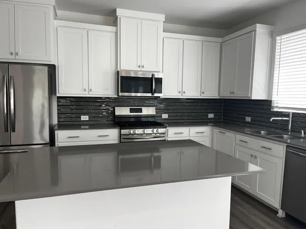 a kitchen with granite countertop a refrigerator sink and white cabinets