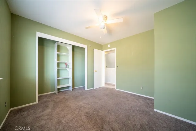 an empty room with closet and a chandelier fan