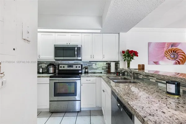 a kitchen with granite countertop a stove top oven microwave and cabinets
