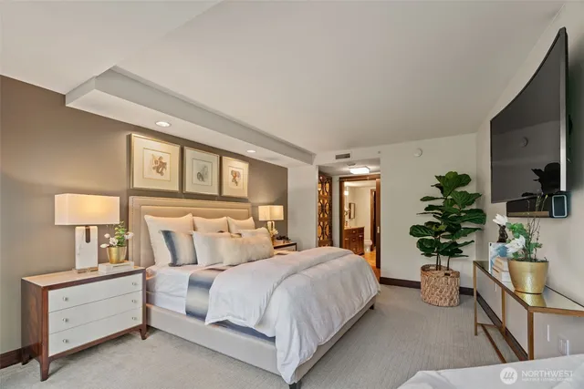 a bedroom with a large bed and a flat tv screen on dresser