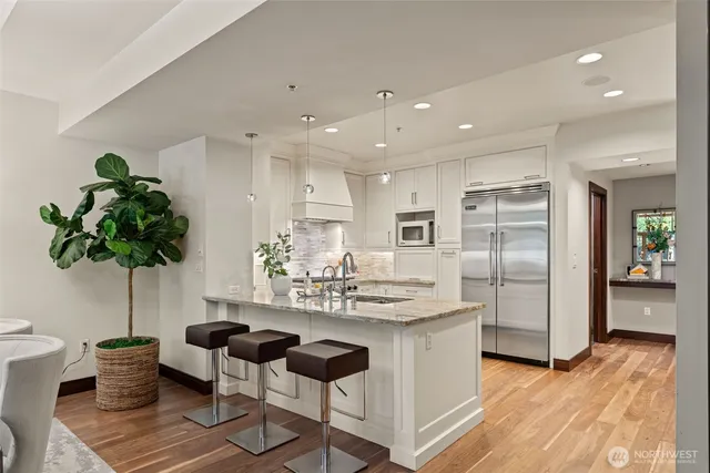 a kitchen with stainless steel appliances kitchen island granite countertop a refrigerator and a sink