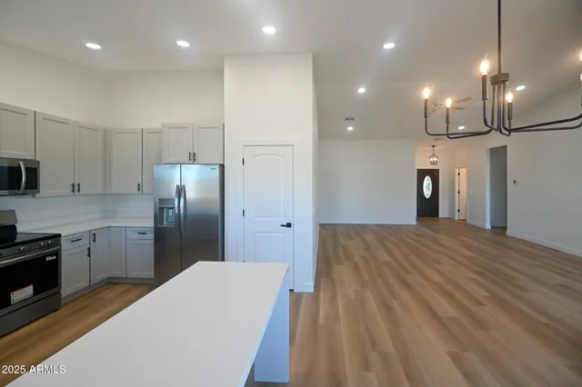 a large kitchen with stainless steel appliances a refrigerator and a wooden floor