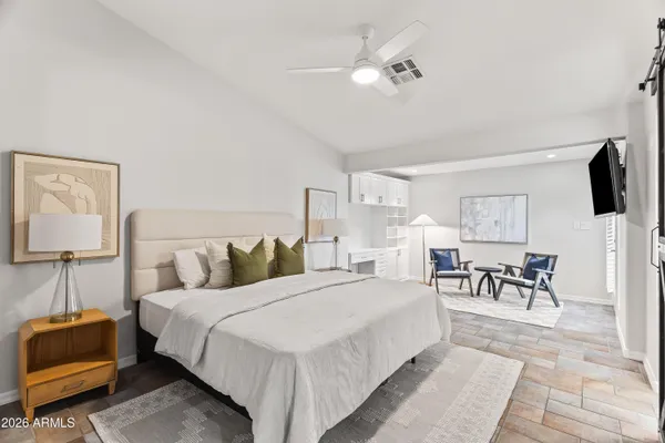 a spacious bedroom with a bed a couch and a chandelier