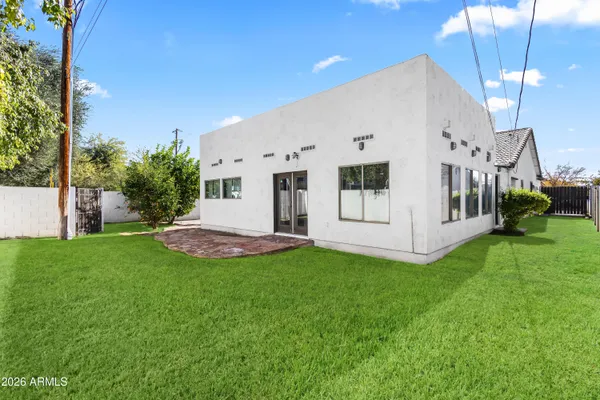 a view of a white house with a big yard potted plants and large tree