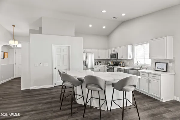 a kitchen with stainless steel appliances a dining table chairs and wooden floor