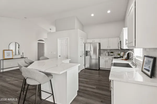 a open kitchen with stainless steel appliances kitchen island granite countertop a sink a stove a refrigerator cabinets and chairs